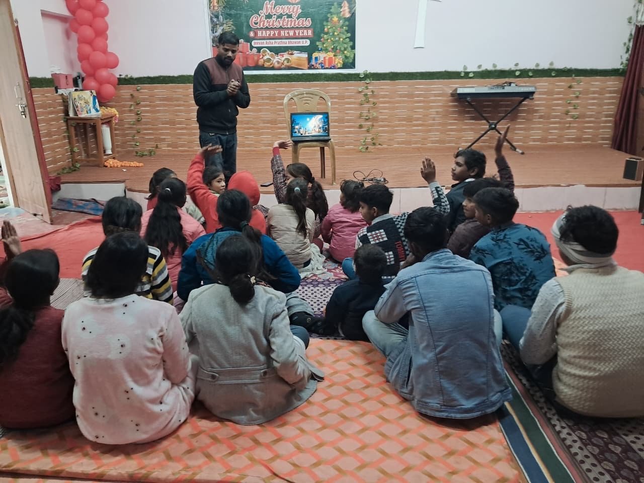 Children raising their hands during an Oikos Kids session in India